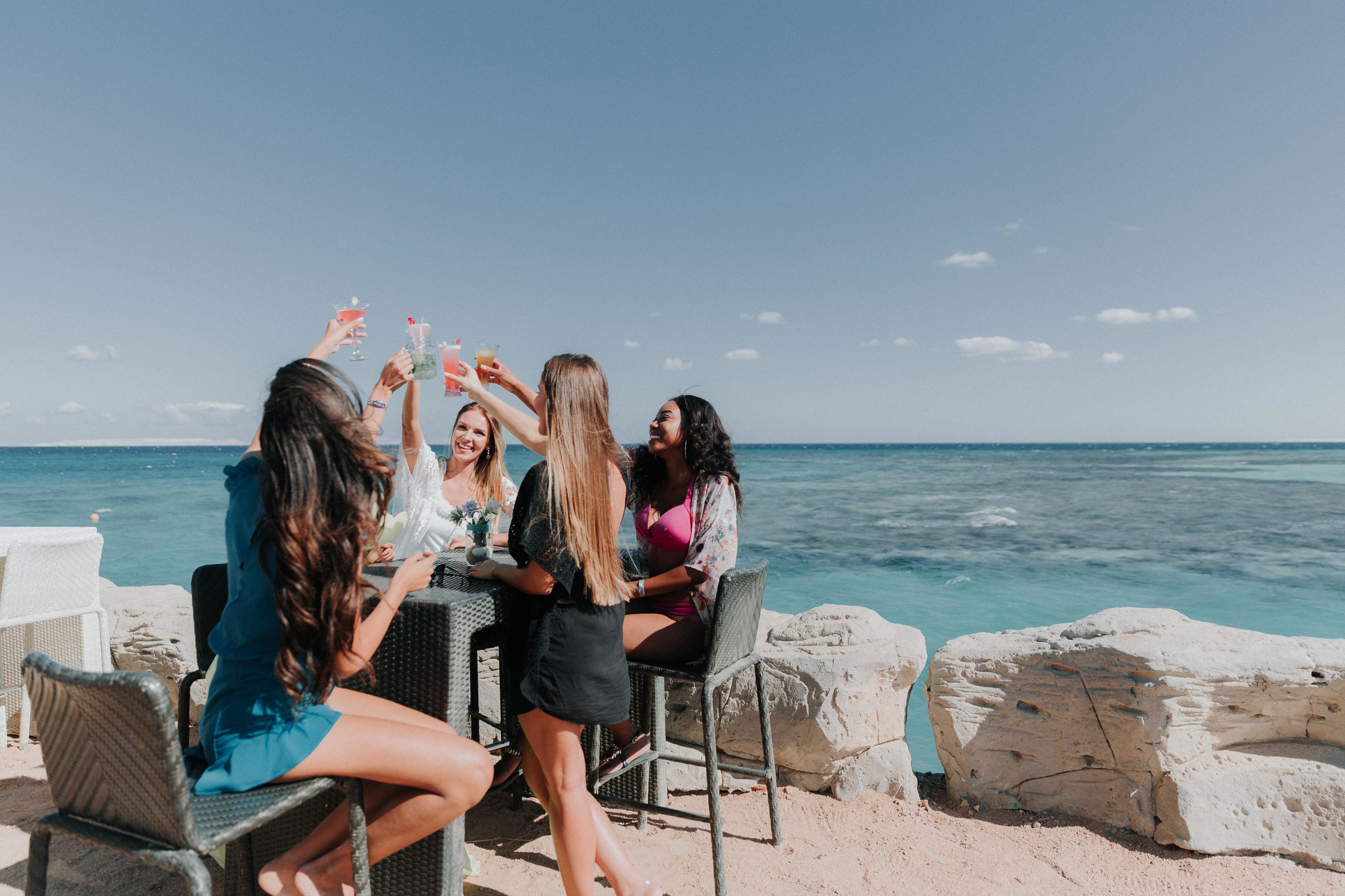 Groepje vrouwen drinkt samen drankje met zeezicht
